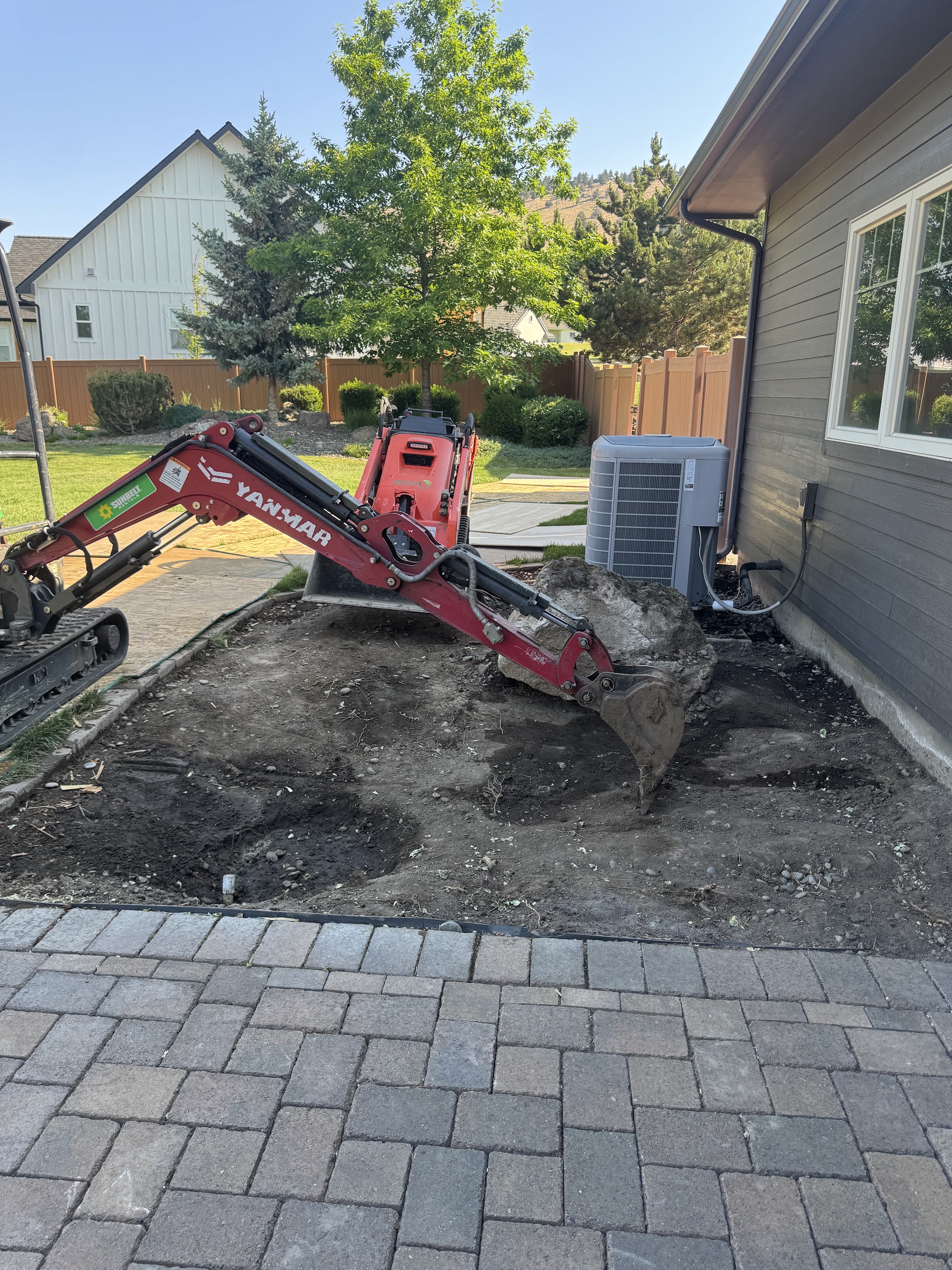 A large finished paver patio behind a blue ranch-style home